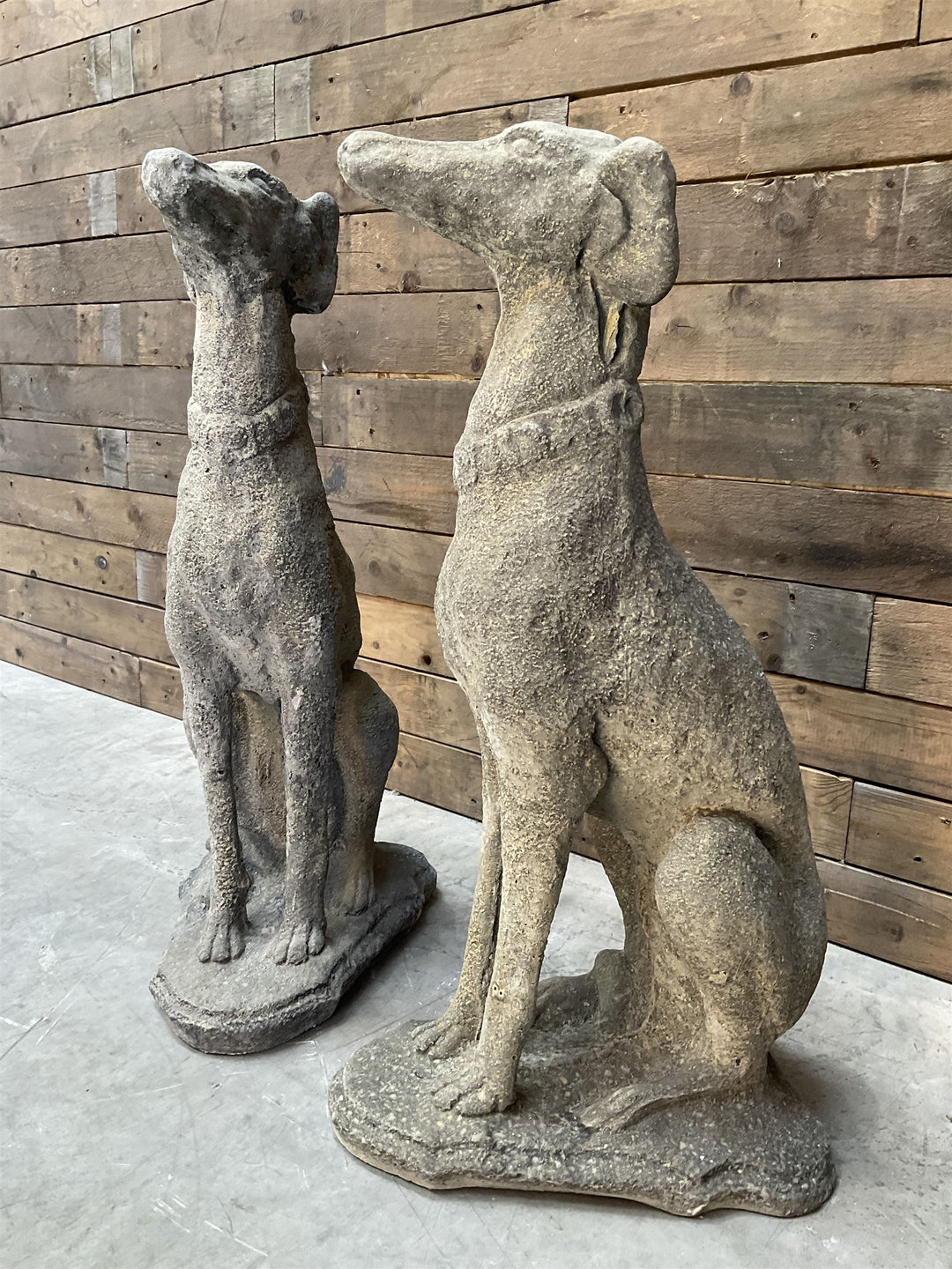 Pair of cast stone French lurchers, seated pose, on shaped plinth